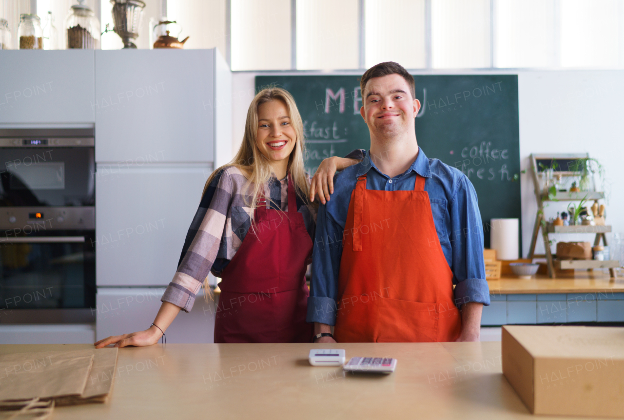 A young Down Syndrome waiter working with colleague in take away restaurant, social inclusion concept.