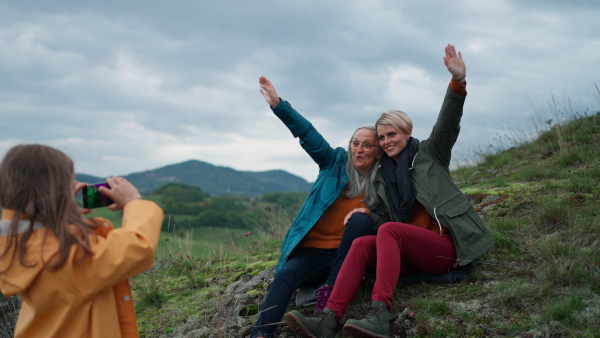 A small girl taking picture of mother and grandmother on top of mountain.