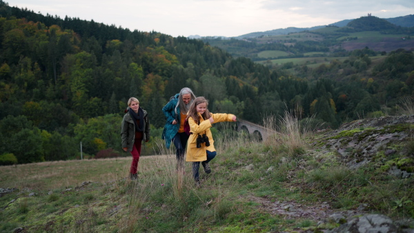 A portrait of small girl with mother and grandmother standing and looking at camera outoors in nature.