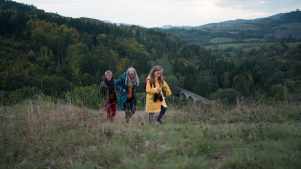 a Small girl with mother and grandmother hiking outoors in nature.