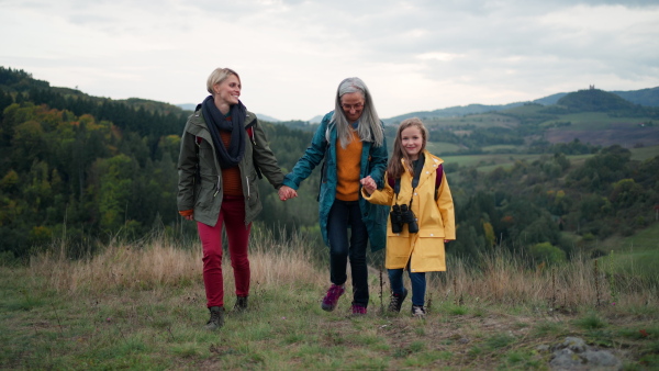 a Small girl with mother and grandmother hiking outoors in nature.