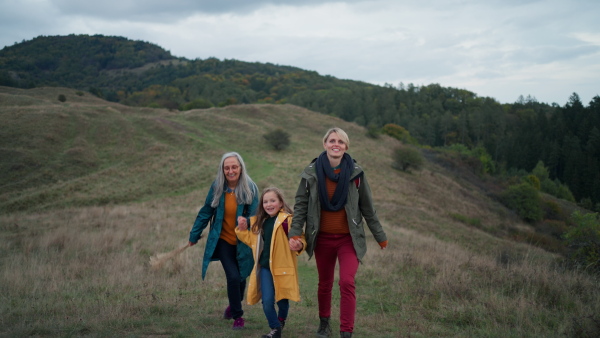 a Small girl with mother and grandmother hiking outoors in nature.