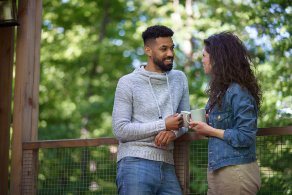 A happy couple resting and looking at camera outdoors in a tree house, weekend away and digital detox concept.