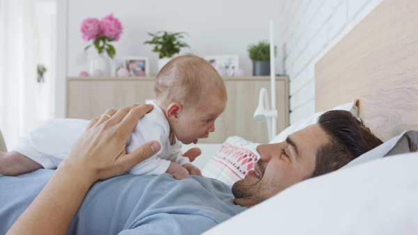 A young father enjoying time together with newborn baby girl at home.