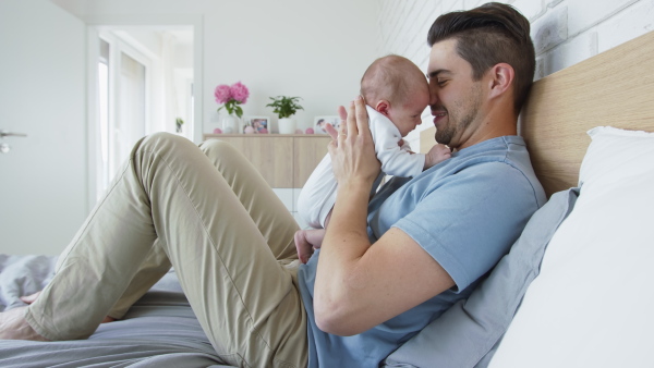 A young father enjoying time together with newborn baby girl at home.