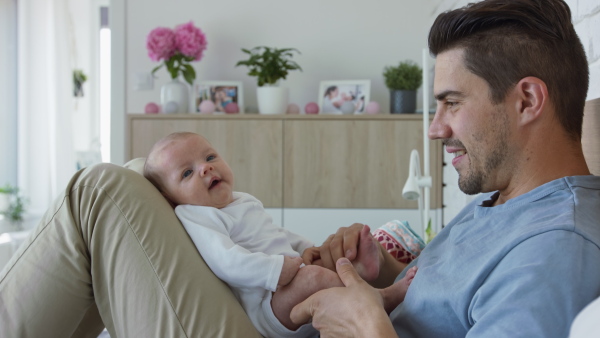 A young father enjoying time together with newborn baby girl at home.