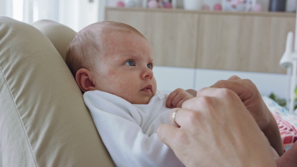 An unrecognizable young father enjoying time together with newborn baby girl at home.