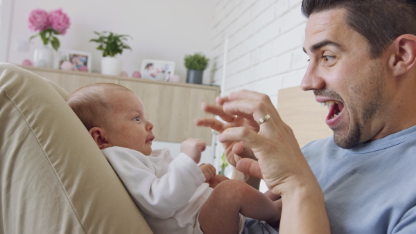 A young father enjoying time together with newborn baby girl at home.