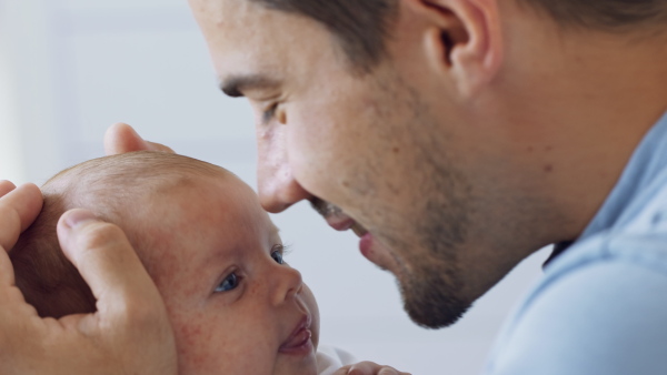 A close up of young father enjoying time together with newborn baby girl at home.