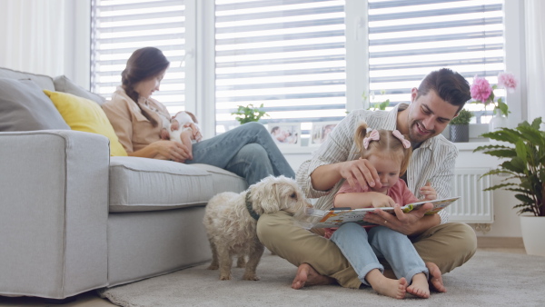 A happy young family with newborn baby and little girl enjoying time together at home.