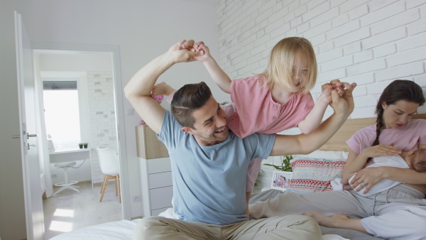 A happy young family with newborn baby and little girl enjoying time together at home.