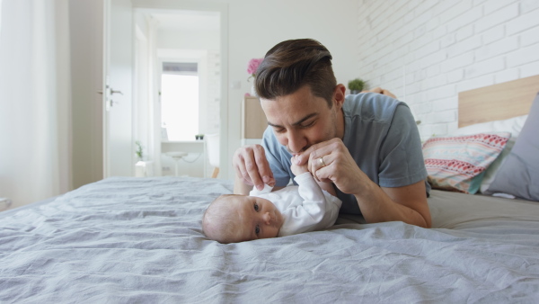 A young father enjoying time together with newborn baby girl at home.