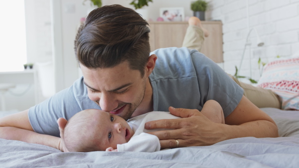 A young father enjoying time together with newborn baby girl at home.