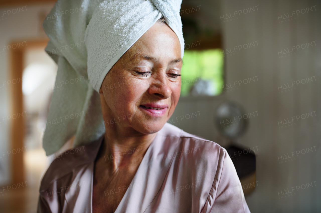 A happy senior women in bathrobe indoors at home, selfcare concept.