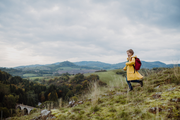 A happy little girl running on the top of mountain outdoors in autumn.