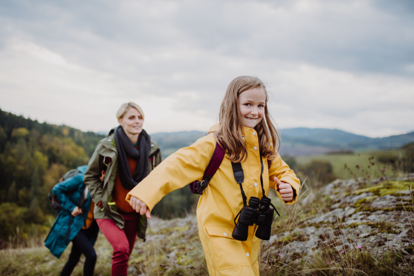 A portrait of small girl with mother and grandmother standing and looking at camera outoors in nature.