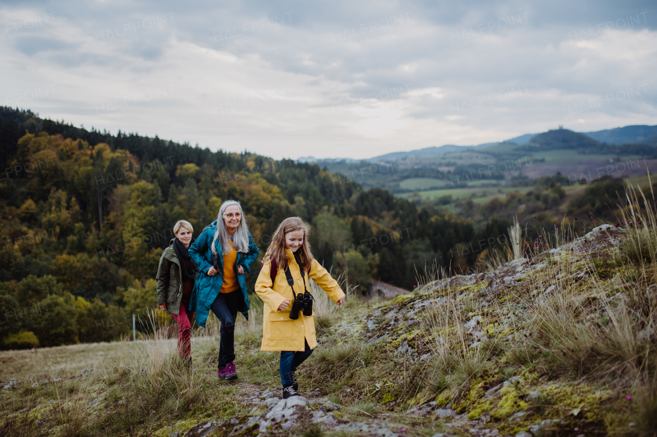 A portrait of small girl with mother and grandmother standing and looking at camera outoors in nature.