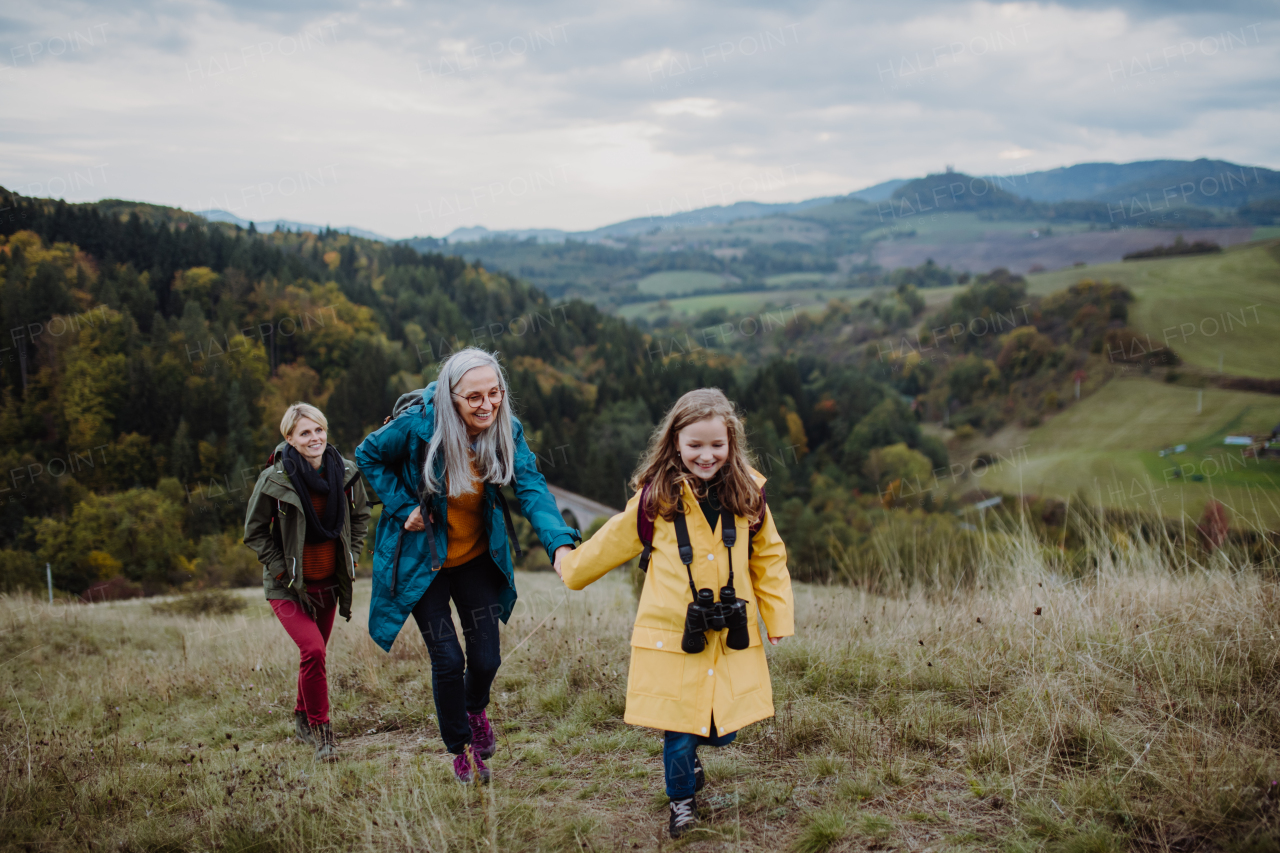 A portrait of small girl with mother and grandmother standing and looking at camera outoors in nature.