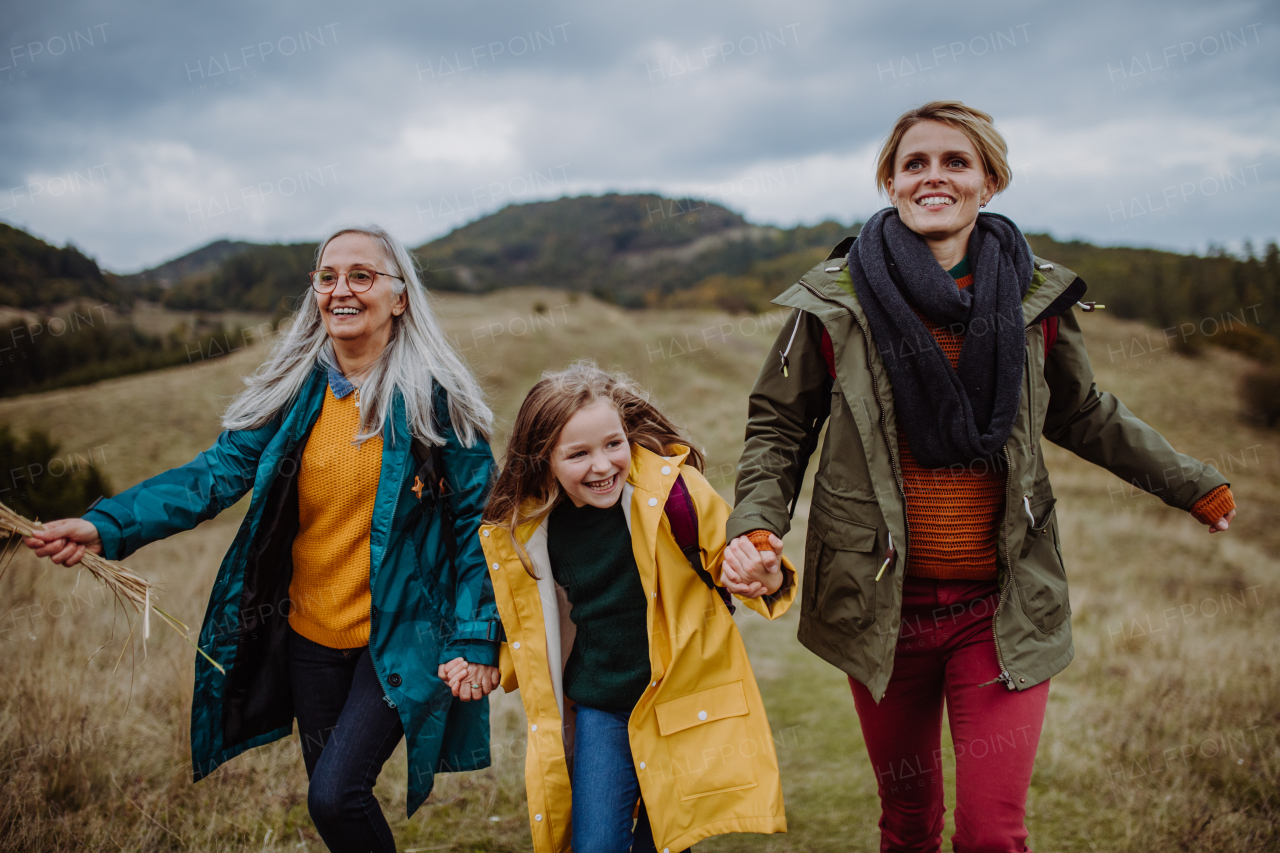 A small girl with mother and grandmother hiking outoors in autumn nature.