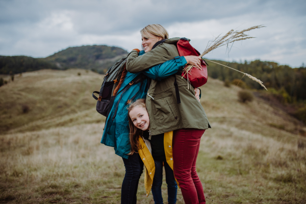 A small girl with mother and grandmother standing and lookiong at view on top of mountain.