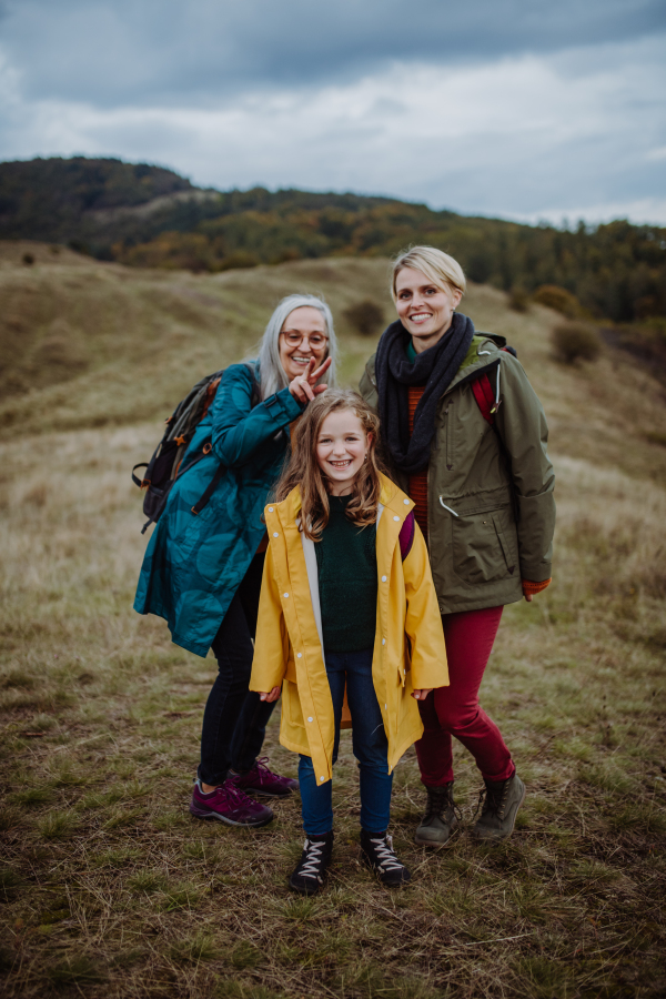 A small girl with mother and grandmother standing and lookiong at view on top of mountain.