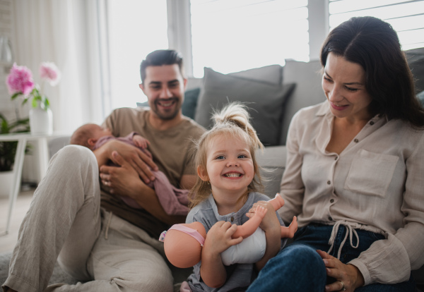 A happy young family with newborn baby and little girl enjoying time together at home.