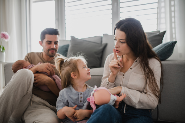 A happy young family with newborn baby and little girl enjoying time together at home.