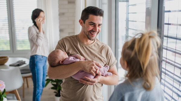 A happy young family with newborn baby and little girl enjoying time together at home.