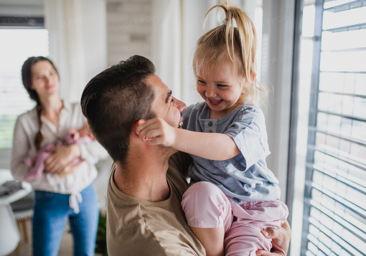 A happy young family with newborn baby and little girl enjoying time together at home.