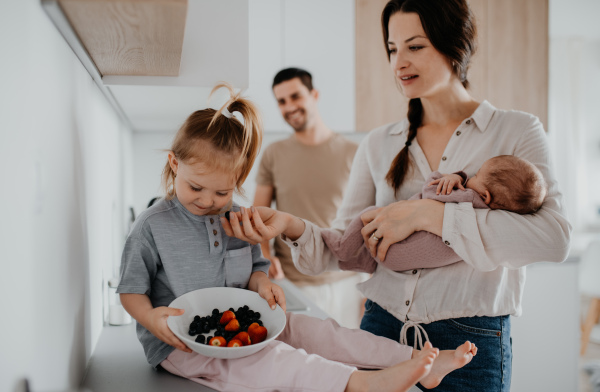 A happy young family with newborn baby and little girl enjoying time together at home, daily routine concept.