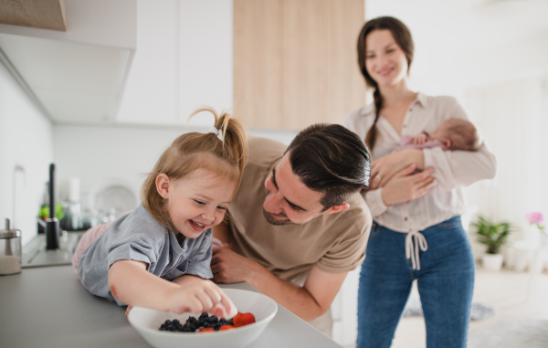 A happy young family with newborn baby and little girl enjoying time together at home, daily routine concept.