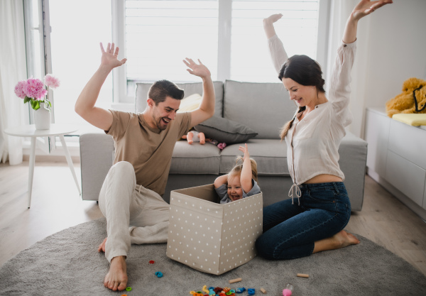 A happy young family with little daughter playing and having fun together at home.