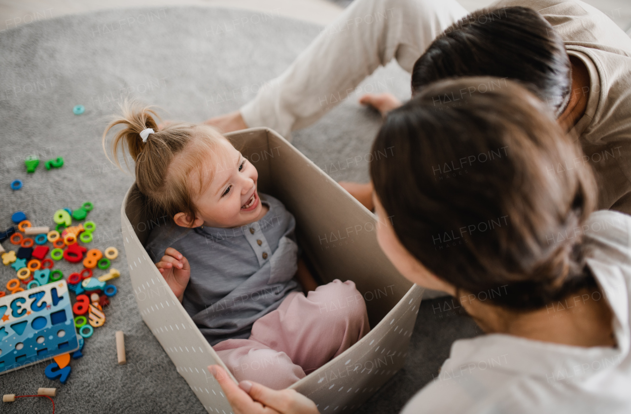 A happy young family with little daughter playing and having fun together at home.