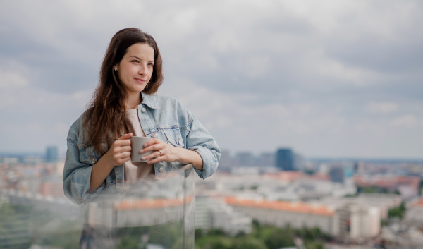 Portrait of a young caucasian woman with coffee outdoors on balcony