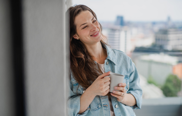 Portrait of a young caucasian woman with coffee outdoors on balcony