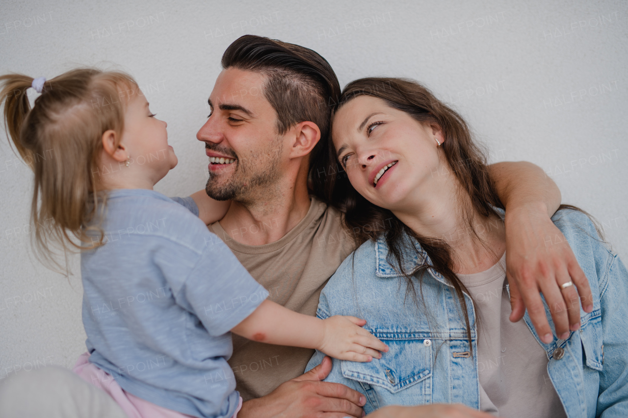 Portrait of happy young parents with a little daughter hugging on white background.