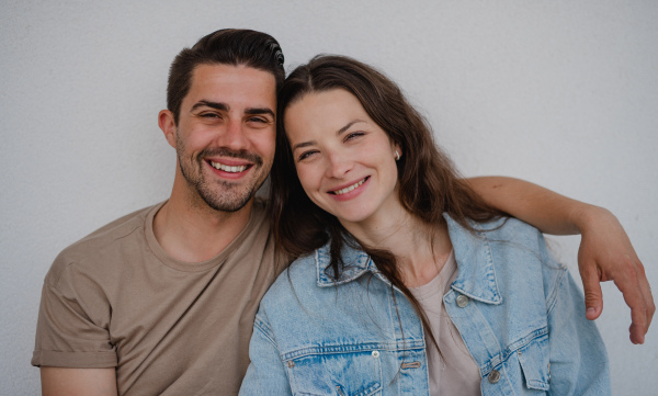 A portrait od happy young couple hugging and looking at camera, on white background.