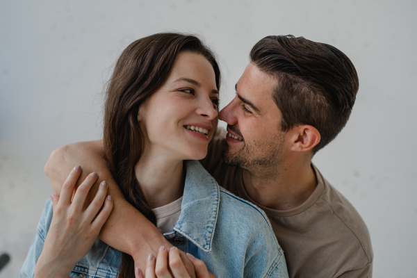 Portrait of a happy young couple hugging and looking at each other, on white background.