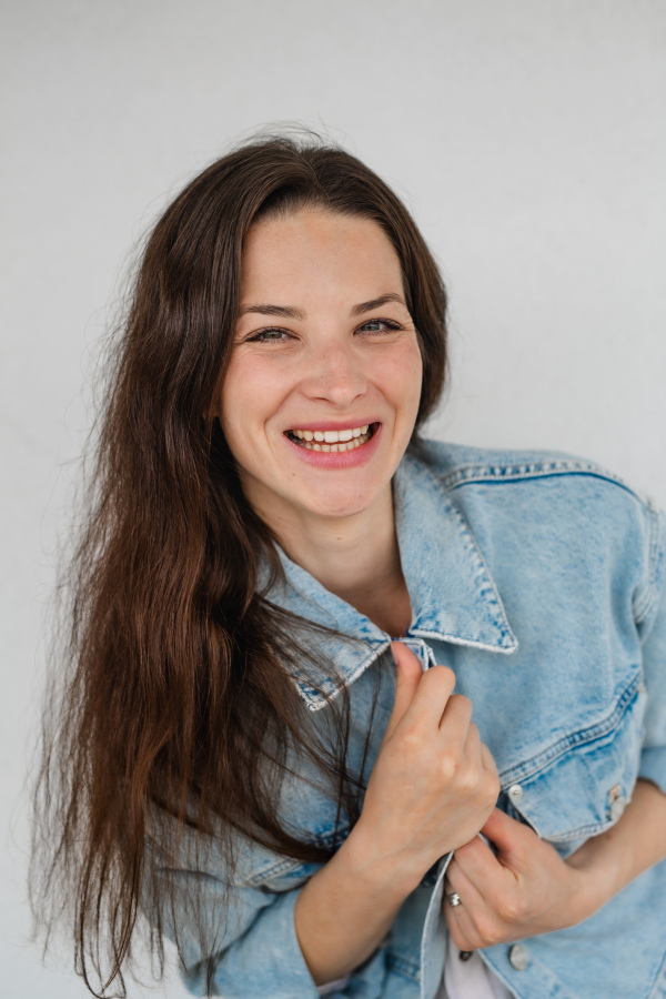 Portrait of a happy young caucasian woman on white background, looking at camera, smiling.