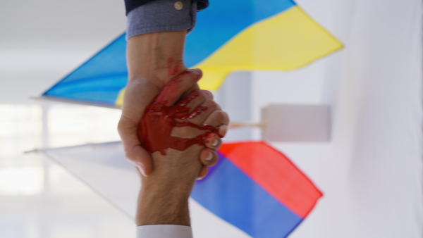 The representatives of Ukraine and Russia shaking hands, blood hand concept.