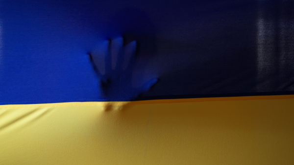 A hand pressing against Ukrainian flag, Ukrainian flag concept.