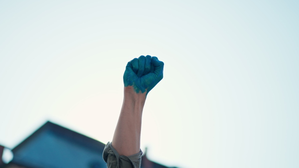 A man with painted hand in blue protesting against Russian invasion in Ukraine in streets, close-up.