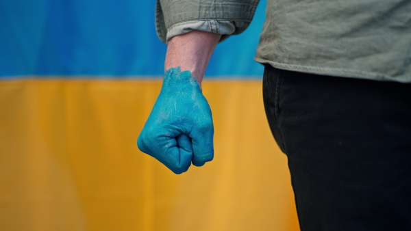 A man with painted hand in blue with Ukrainian flag protesting against Russian invasion in Ukraine in streets, close-up.