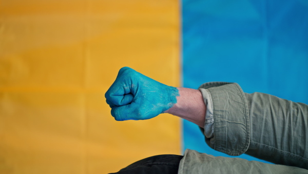 A man with painted hand in blue with Ukrainian flag protesting against Russian invasion in Ukraine in streets, close-up.