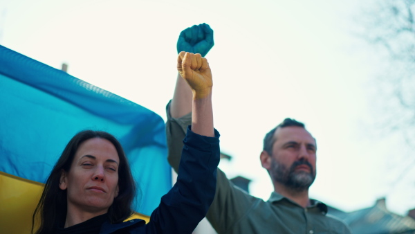 People raising hands and protesting against Russian invasion in Ukraine in streets together.