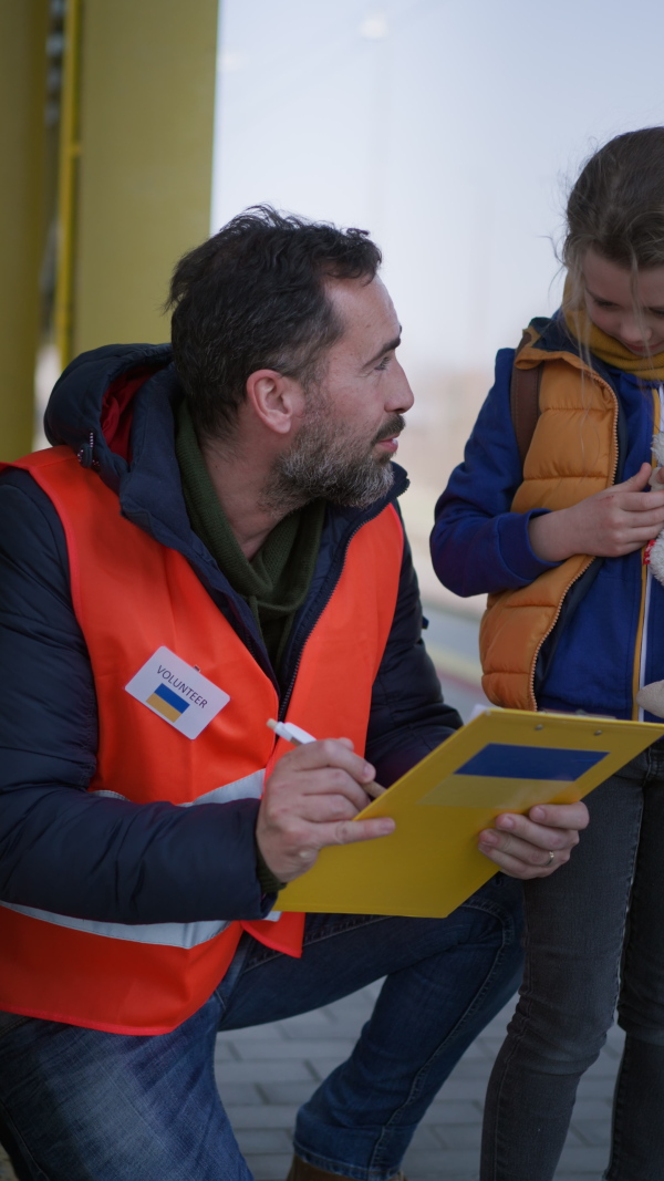 A vertical footage of volunteer registring Ukrainian refugees at train station.