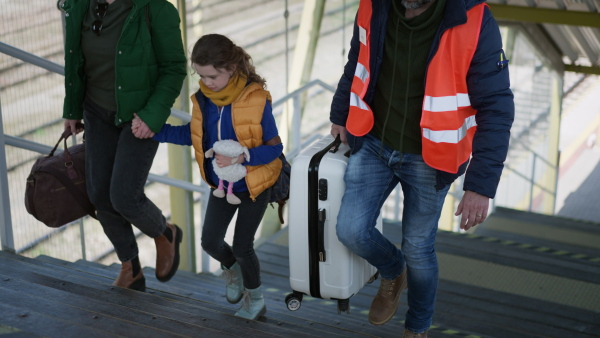 A volunteer helping Ukrainian mother with child, refugees, at train station.