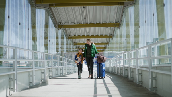 An Ukrainian immigrant mother with child with luggage walking at train station, Ukrainian war concept.