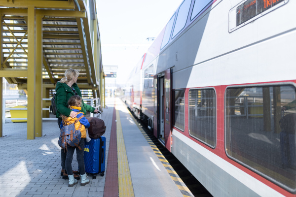 An Ukrainian immigrant family with luggage waiting at train station, Ukrainian war concept.