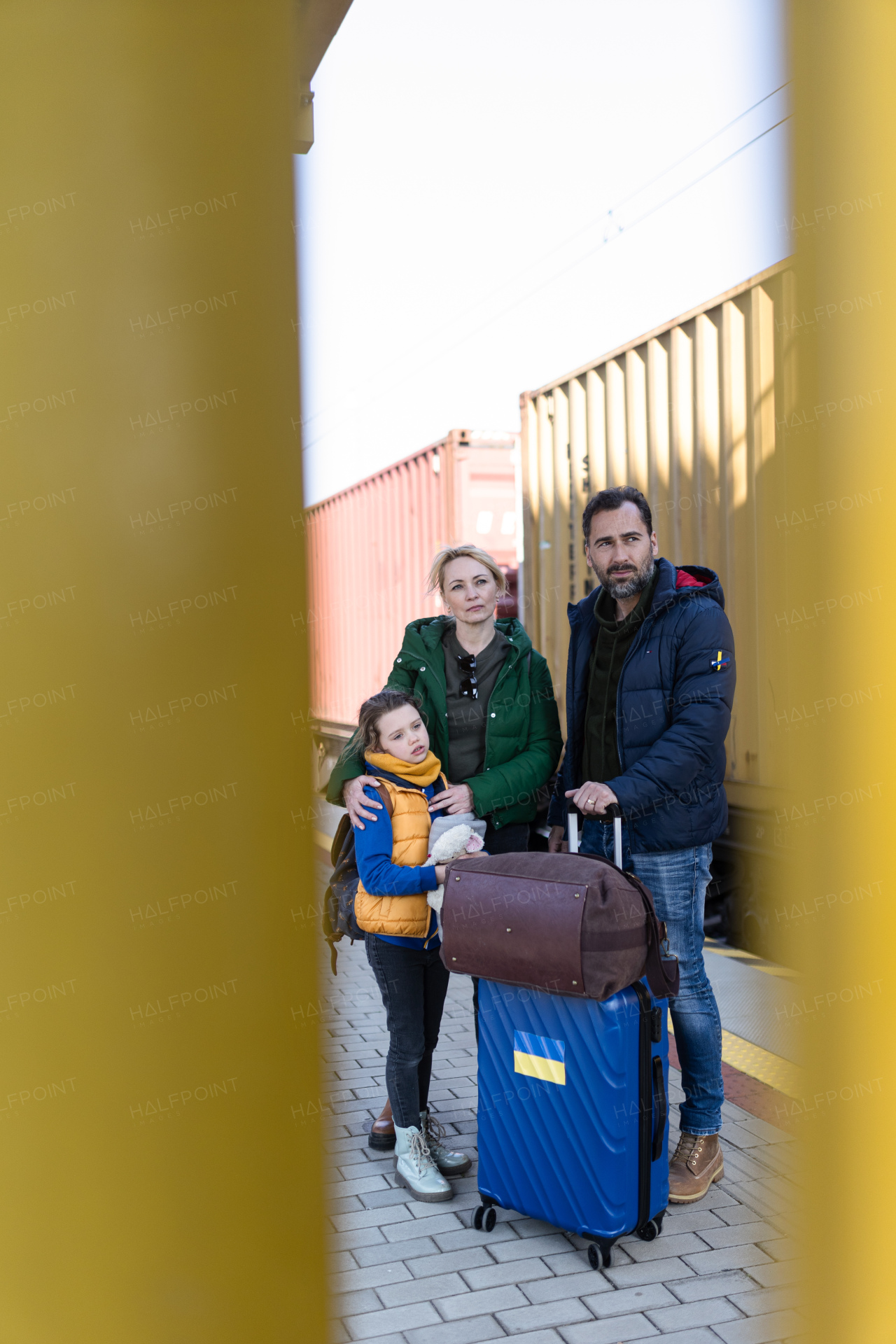 An Ukrainian refugee family with luggage at railway station together, Ukrainian war concept.